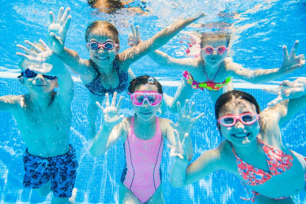 Kids swimming underwater in a clear backyard pool